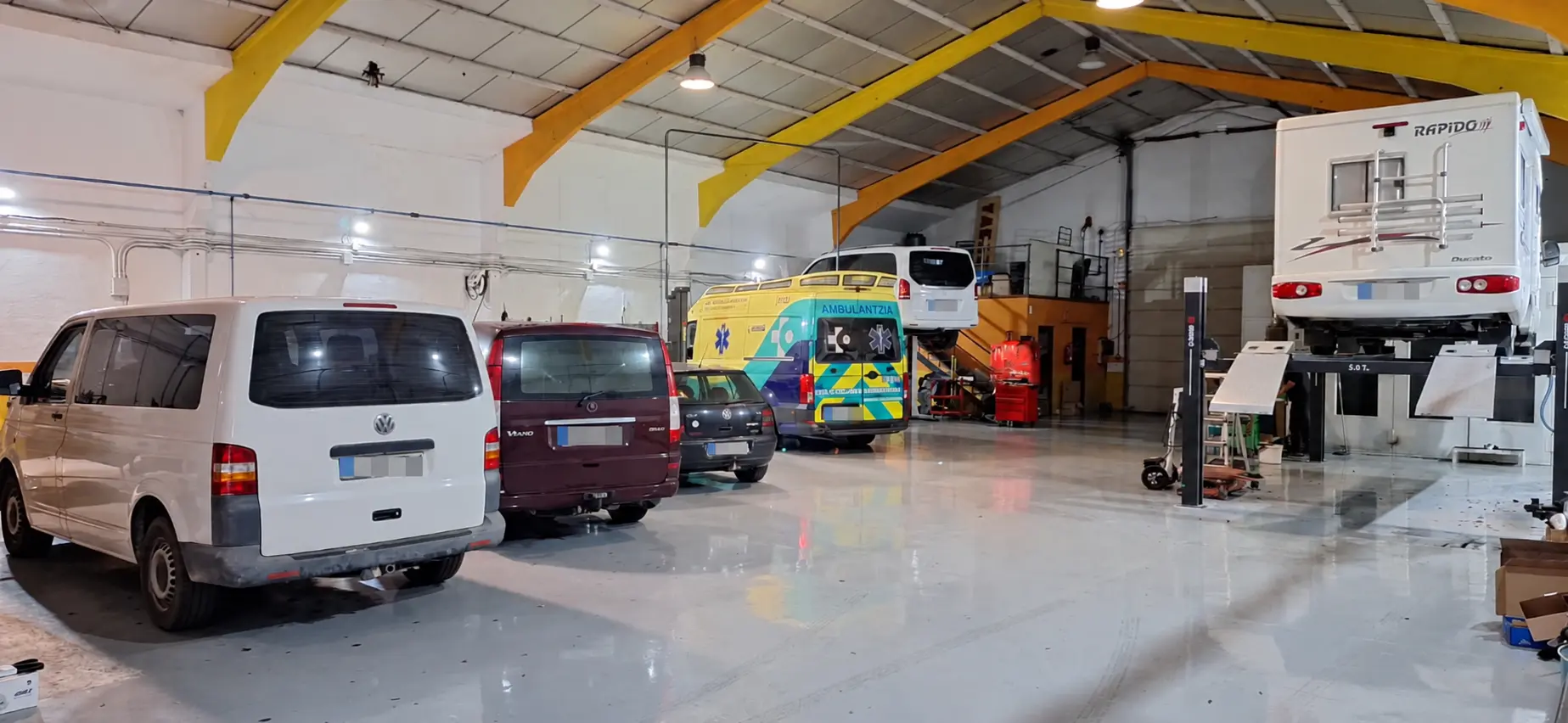 Interior del taller Hiruko Motor con furgonetas, ambulancia y autocaravana